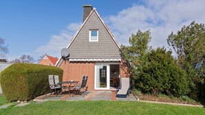Une maison avec un toit en pente, une cheminée et une petite fenêtre.