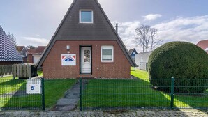 Un petit bâtiment à toit triangulaire, doté d’une façade en briques, d’une petite fenêtre et d’une porte. On peut y voir une enseigne et un panneau indiquant le numéro « 5 ».