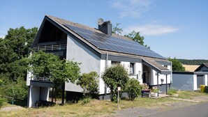 A modern house with a sloped roof, solar panels, and a satellite dish. - Light-flooded architect house in a quiet location FeWo "Red" (Edertal)