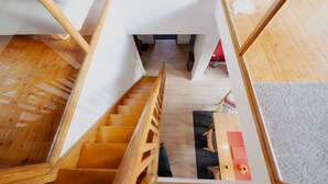 A wooden staircase leading to a room with a black rug and a red chair. - Light-flooded architect house in a quiet location FeWo "Red" (Edertal)