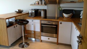 A modern kitchen with a central island, built-in oven, and stainless steel appliances. - Doëlan: Charming house facing the sea  (Clohars-Carnoët)