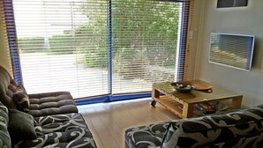 A living room with a sofa set, a small wooden table with a bowl, and a TV mounted on the wall. - Doëlan: Charming house facing the sea  (Clohars-Carnoët)