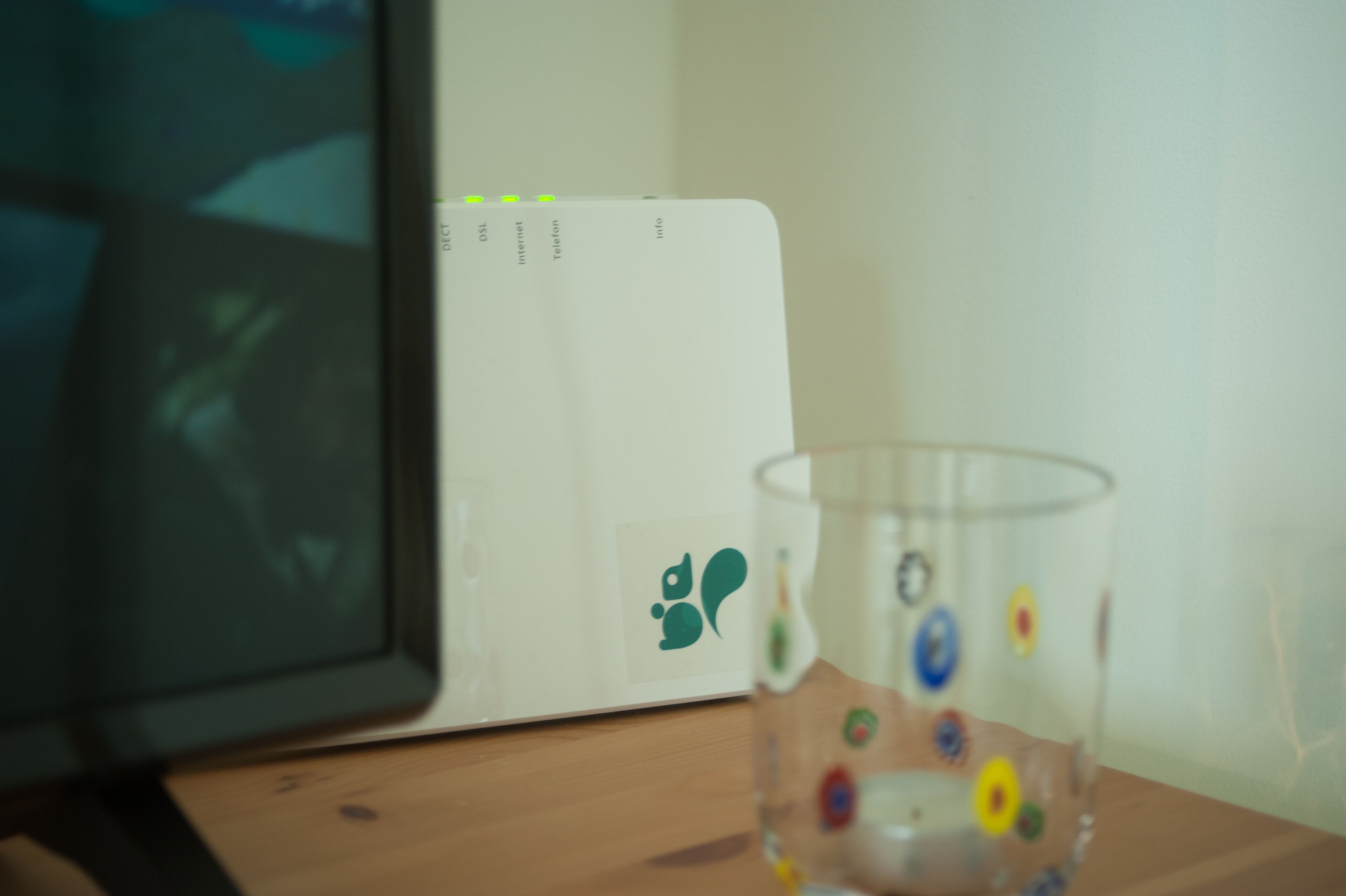 A computer monitor, a glass with colorful stickers, and a white card with icons.