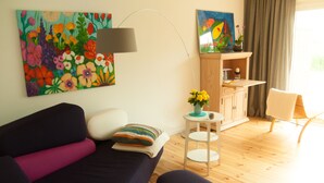 En moderne stue med en sofa, et lille bord med en vase blomster, en lampe og et skab.