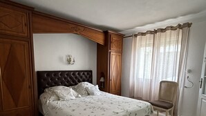 A bedroom with a large bed, wooden wardrobe, and a chair. - Fenced garden with 10x4 pool, 85m2 terrace and shaded terrace (Générac)