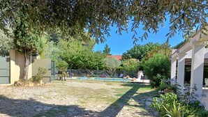 A backyard with a swimming pool, a covered patio area, and a variety of plants and trees. - Fenced garden with 10x4 pool, 85m2 terrace and shaded terrace (Générac)