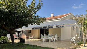 A covered patio area with outdoor seating and a view of the house. - Fenced garden with 10x4 pool, 85m2 terrace and shaded terrace (Générac)