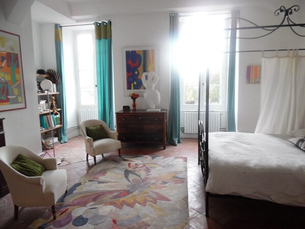 A bedroom with a bed, a chair, a dresser, a bookshelf, and a colorful rug.