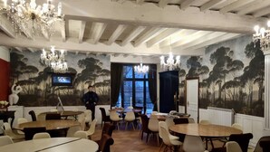 A dining area with multiple round tables and chairs, a chandelier, and a mural of trees on the walls. - an unusual and Design Chateau (Pech- Luna)