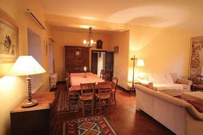 Un salon chaleureux avec une table à manger, des chaises, un canapé et une lampe.