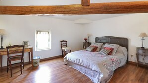 Une chambre à coucher avec un lit en bois, un bureau avec une chaise, une fenêtre et une table de chevet avec une lampe.