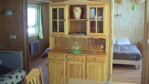 Een houten blokhut van binnen, met een eethoek, een bed en een kleine keuken.