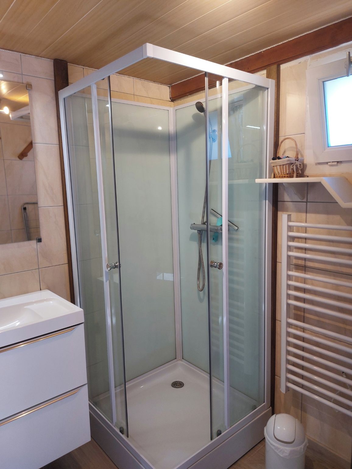 Une salle de bain moderne avec une douche à parois de verre, un lavabo blanc et un porte-serviettes.