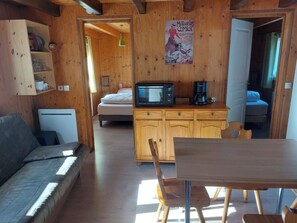 Ett mysigt rum med träinredning, en soffa, ett matbord, en mikrovågsugn och ett skåp.