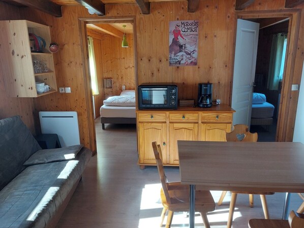 A cozy room with a wooden interior, a sofa, a dining table, a microwave, and a cabinet.