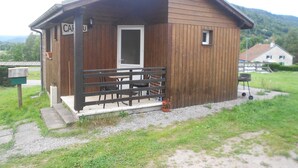 Een houten hut met een veranda, een deur en een klein raam.