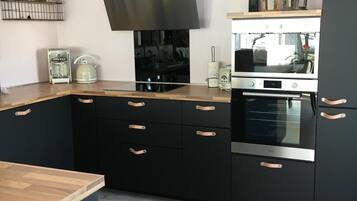 A modern kitchen with black cabinets, a stainless steel range hood, and a built-in oven.