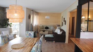 A modern living room with a wooden floor, a dining table, and a sofa set. - Detached house 3 Bedrooms, 140 M2, Loggia, Balcony, private garden 800 M2 (Les Hôpitaux-Neufs)