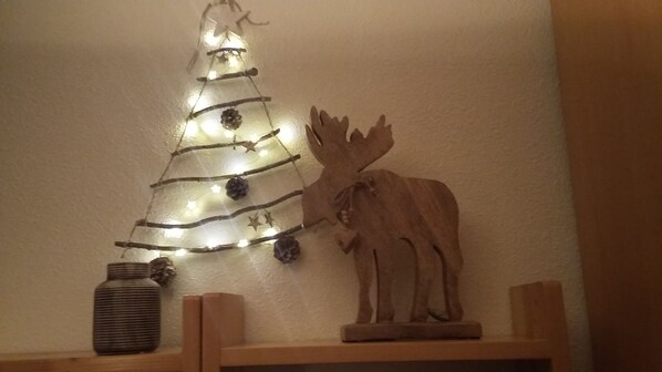Decorative shelf featuring a vase, reindeer sculpture, and a stylized Christmas tree with string lights.
