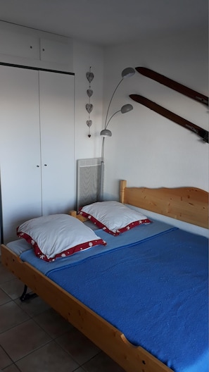 Cozy retreat with a comfortable bed, white wardrobe, and ski storage.