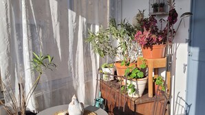 A small balcony with a table, chairs, potted plants, and a birdcage. - T2 apartment with south-facing terrace (Cotignac)