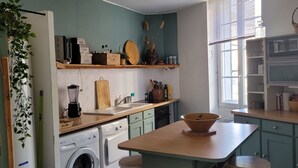A compact kitchen with a washing machine, a sink, and a wooden table with a bowl. - T2 apartment with south-facing terrace (Cotignac)