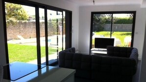 A living room with a sofa, a TV, and a sliding glass door leading to a backyard.