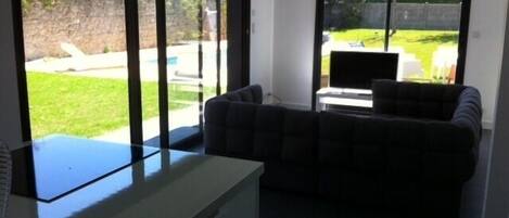 A living room with a sofa, a TV, and a sliding glass door leading to a backyard.