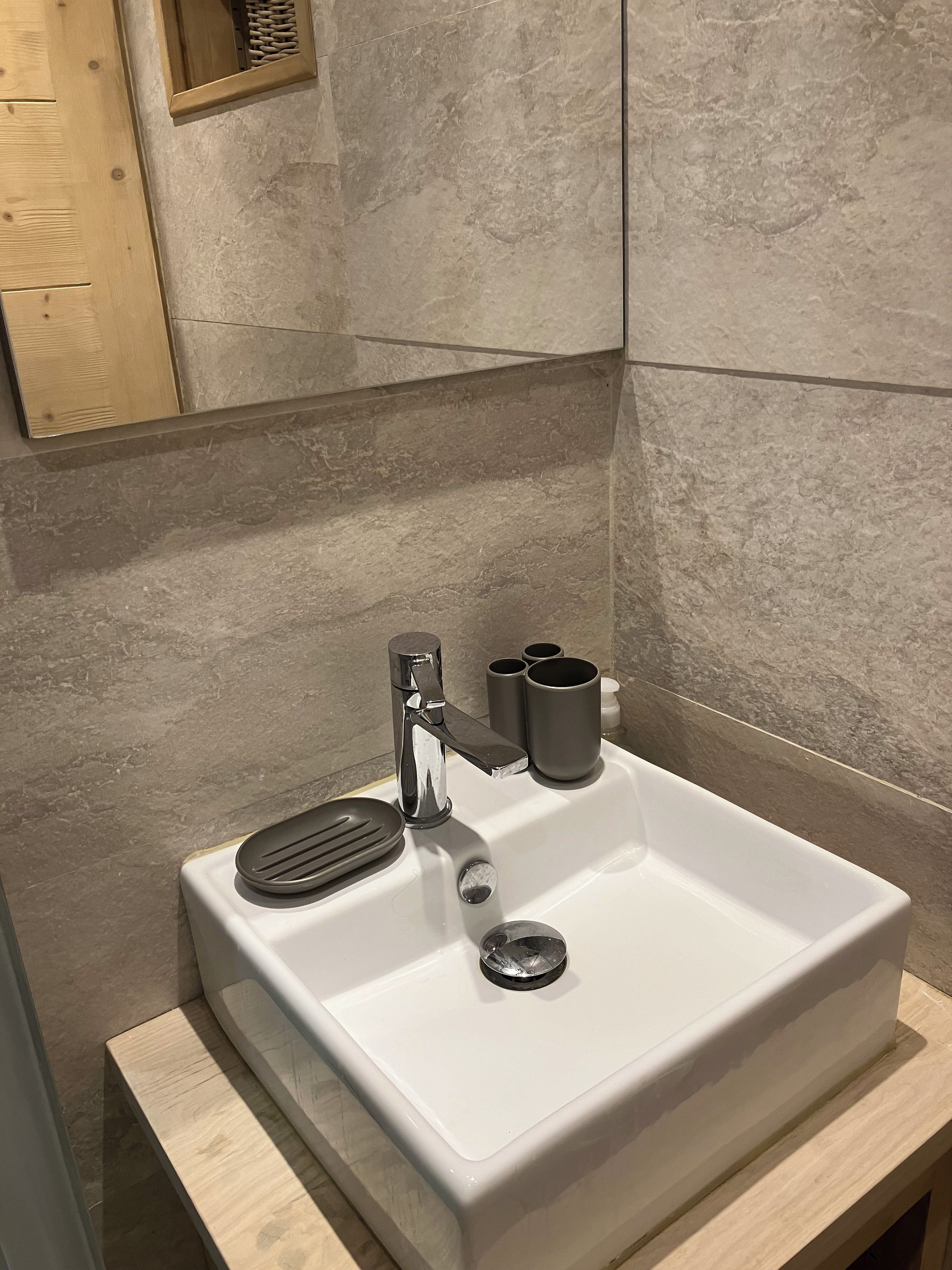 A bathroom with a white sink, a modern faucet, and a small mirror above it.
