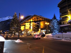 A hotel with a stone facade, large windows, and a balcony overlooking a snowy mountain.