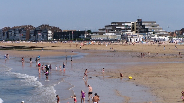 A beach with people walking and playing, buildings in the background, and a clear sky. -  STUDIO SEASIDE 30 METERS FROM THE EXPOSURE DUE SOUTH BEACH  (Courseulles-Sur-Mer)