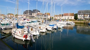 A marina with multiple boats docked, surrounded by residential buildings. -  STUDIO SEASIDE 30 METERS FROM THE EXPOSURE DUE SOUTH BEACH  (Courseulles-Sur-Mer)