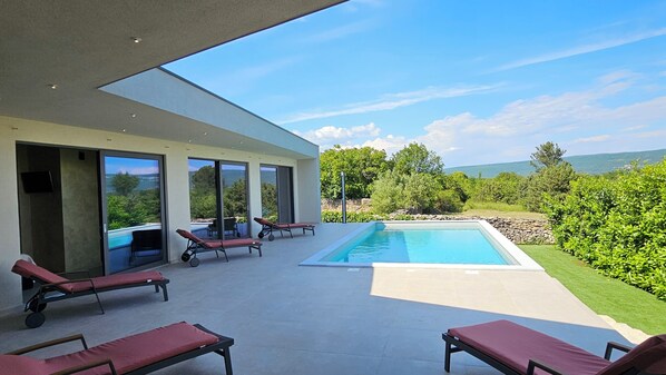 Ein moderner Poolbereich im Freien mit Liegestühlen und Blick auf die Landschaft.