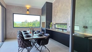 A modern dining area with a large window, a black-tiled backsplash, and a view of greenery. - Stylish villa *****, heated pool (Rakalj)