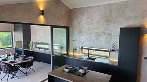 A modern kitchen with a large window, dark cabinetry, and a built-in stove. - Stylish villa *****, heated pool (Rakalj)