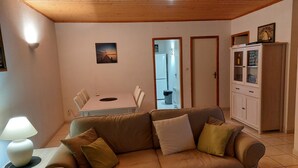 A cozy living room with a brown sofa, a dining table, and a cabinet. - .Maison Quiet, sunny position good in 10 'from the beach residence (Fleury)