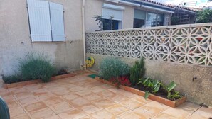 A patio with tiled flooring, a decorative fence, and various potted plants. - .Maison Quiet, sunny position good in 10 'from the beach residence (Fleury)