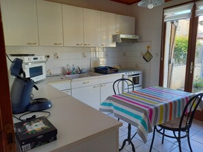 A kitchen with white cabinets, a microwave, a stove, and a table with a striped tablecloth.