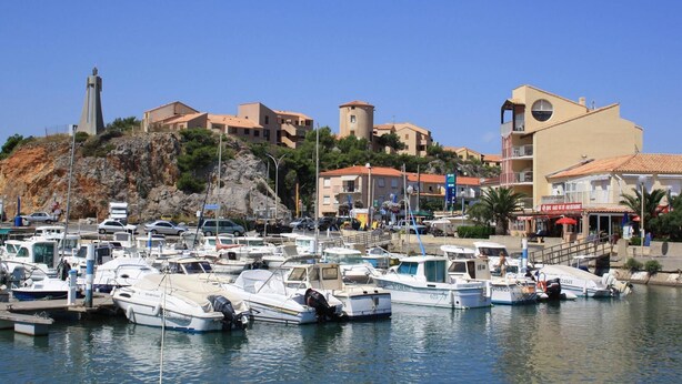 A marina with boats docked, buildings with Mediterranean architecture, and a prominent tower structure. - .Maison Quiet, sunny position good in 10 'from the beach residence (Fleury)