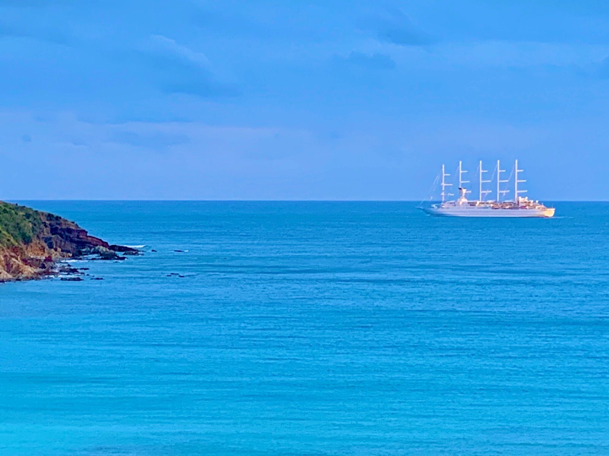 A large ship with multiple sails on the ocean.