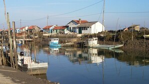 A calm waterfront with boats docked, wooden structures, and houses with red roofs. - Charming house near the beach, detached, not overlooked, WIFI. (Arvert)