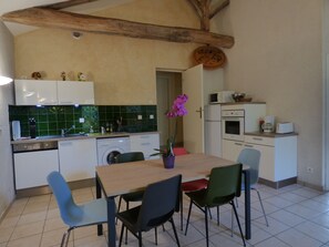Cocina compacta con comedor, que cuenta con una viga de techo de madera, lavadora y microondas.