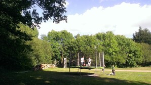 A park with a trampoline and a basketball court.