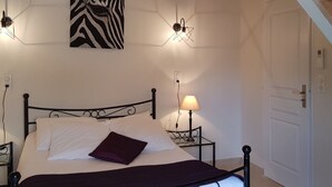 Un dormitorio con una cama, un cuadro con estampado de cebra, dos lámparas de pared y una puerta.