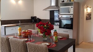 Cocina moderna con una mesa de comedor preparada para cuatro personas, equipada con microondas, horno y una campana extractora grande.