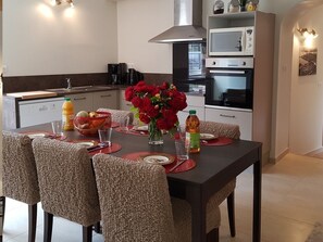 Une cuisine moderne avec une table à manger pour quatre personnes, équipée d’un four à micro-ondes, d’un four traditionnel et d’une hotte aspirante de grande taille.