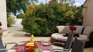 Un área de comedor al aire libre con una mesa dispuesta para cuatro personas, rodeada de sillas.