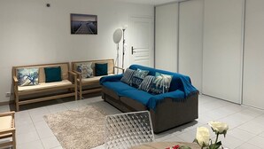 Una sala de estar moderna con un conjunto de sofás, una mesa de comedor y un ventanal grande.