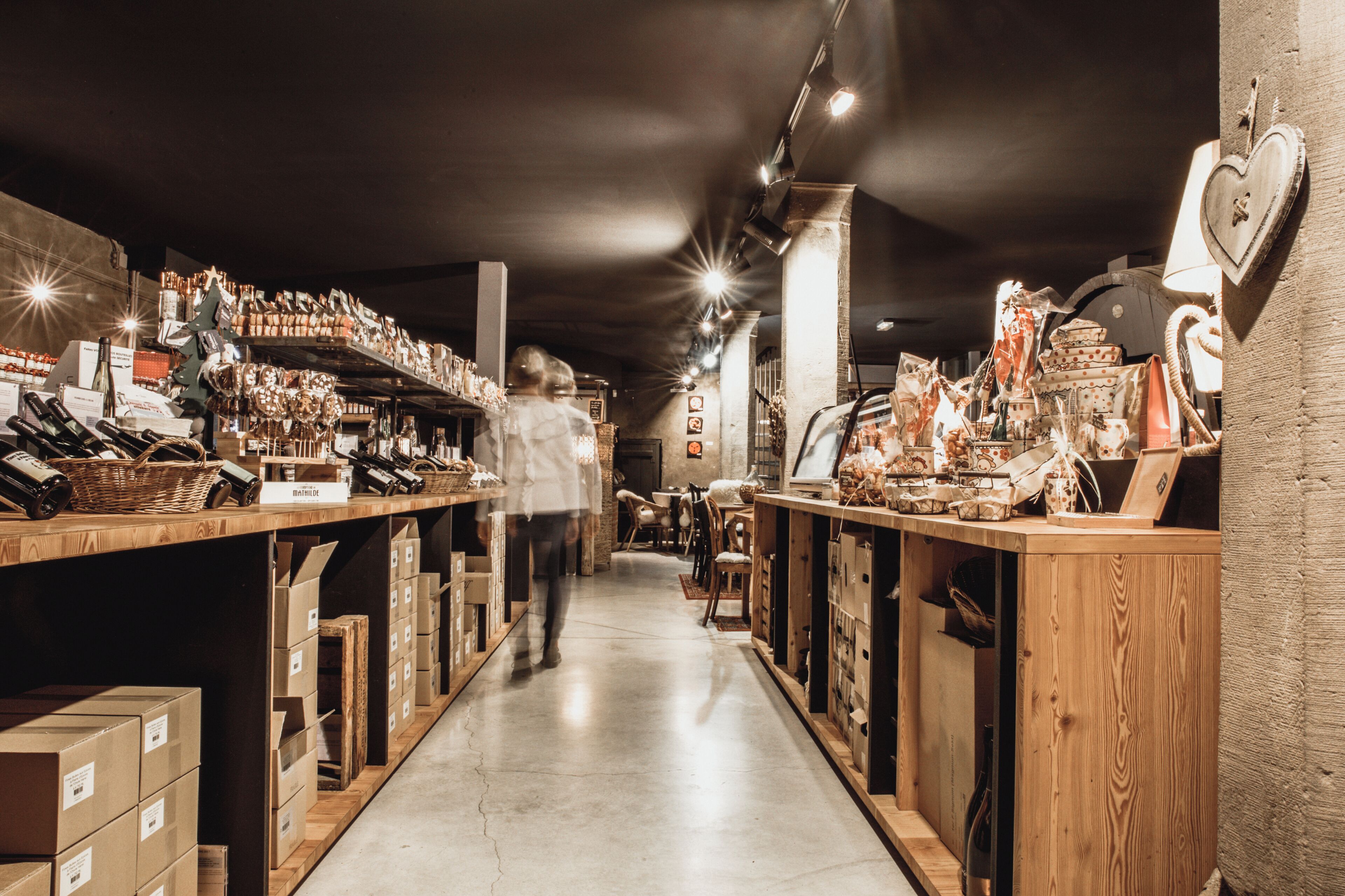 A narrow aisle with shelves on either side displaying various items.