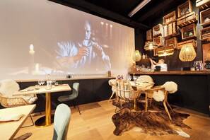 A bar area with a projection screen, wooden crates, and a bar counter. - La distillerie - House at the foot of the vines with garden 6personnes (Gertwiller)